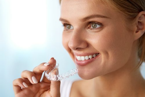 Closeup Of Woman With Straight Teeth Holding Invisible Braces