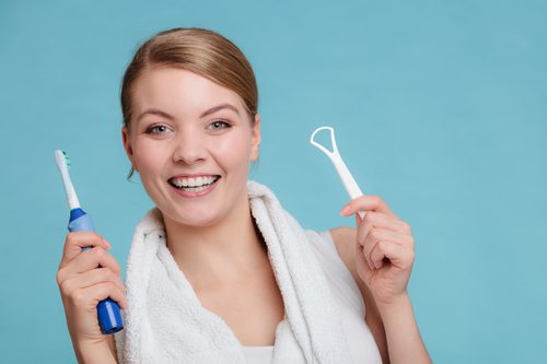 young woman with electric toothbrush and tongue cleaner