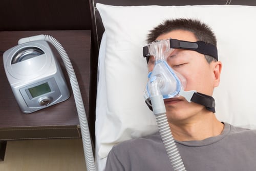 Man with sleep apnea using CPAP machine